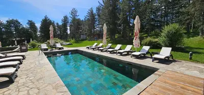 a swimming pool with lounge chairs and umbrellas at Green Peaks Suite in Pirin Golf & County Club in Razlog