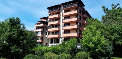 a tall building with trees in front of it at Апартаменти Мечето in Sandanski