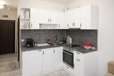 a white kitchen with white cabinets and a sink at Апартаменти Мечето in Sandanski