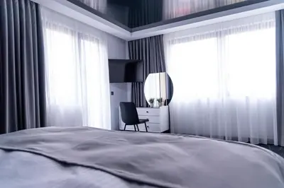 a bedroom with a bed and a chair and windows at A-Dent luxury apartments & Dental Clinic in Gotse Delchev