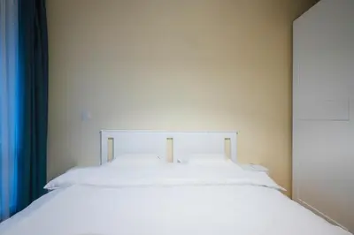 a white bed in a room with a blue curtain at Bright and Cosy 1BD Flat - Perfect for Business Trip by Flat Mаnager in Sofia