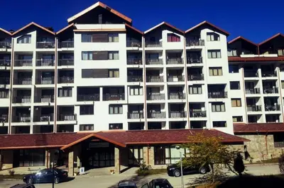 a large white building with cars parked in a parking lot at Borovets gardens Studio A12 in Borovets