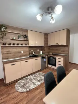 a kitchen with white cabinets and a table and chairs at Двуспален апартамент в к-с Пирин Палас in Bansko