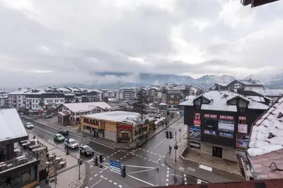 a city with a street with cars and buildings at Двуспален апартамент в к-с Пирин Палас in Bansko