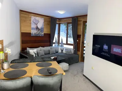 a living room with a table and a couch at Elizi1winter apartments Pamporovo in Pamporovo