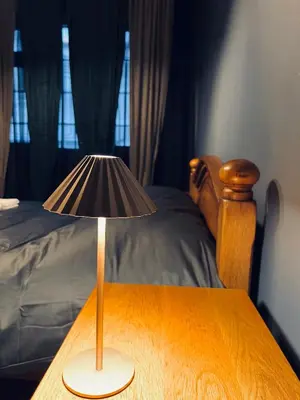 a lamp on a wooden table next to a bed at Central Apartment Black Cat in Karlovo