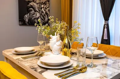 a table with plates and glasses and a vase with flowers at Apollo Apartment close to Medical University in Plovdiv