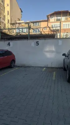 a parking lot with two cars parked next to a white wall at Central, brand new apart with parking in Blagoevgrad