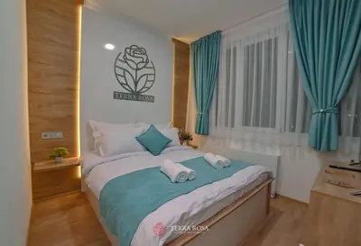 a bedroom with a large bed with blue curtains at Хотел Терра Роза in Karlovo