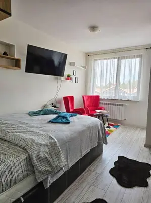 a bedroom with a bed and two red chairs at Boutique Studio B37 in Borovets