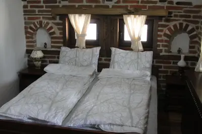 a bed with white sheets and pillows in a bedroom at Шапкова Къща in Delchevo