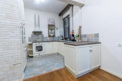 a kitchen with white cabinets and a brick wall at Two Homelike Apartments by NDK and Vitosha Blvd with 2 Free Parking Spots in Sofia