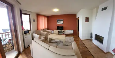 a living room with couches and a table and a television at Gri's place in Bansko