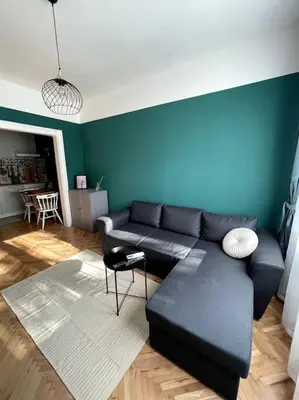 a living room with a black couch and a blue wall at Green Flat Sofia Historic Center in Sofia