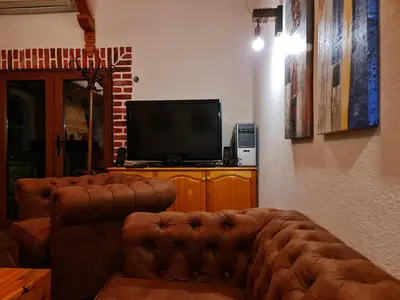 a living room with a couch and a television at СПА къща за гости Каза Роза - Swiss Style Chalet Casa Rosa SPA Guest House in Kyustendil