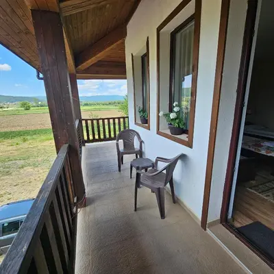 a porch of a house with two chairs and a window at Guest House Belchin View in Belchin