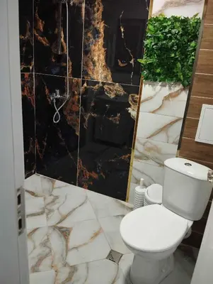 a bathroom with a toilet and a marble wall at Апартамент за гости Боляри 2 in Velingrad