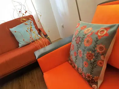 an orange couch with two pillows on it at Bansko Ski Apartments in Bansko Royal Towers in Bansko