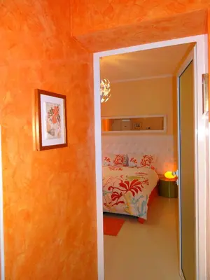 a bedroom with a bed with an orange wall at Orange Flower Apartments 1 in Sofia