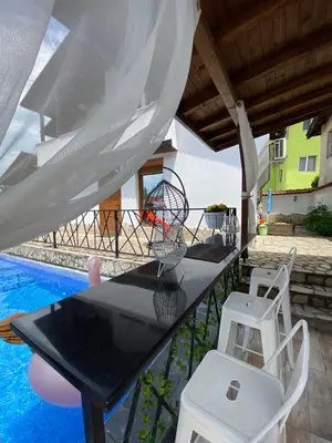 a table and chairs on a patio with a pool at Къща за гости Casa Per Te село Огняново - село Марчево in Marchevo