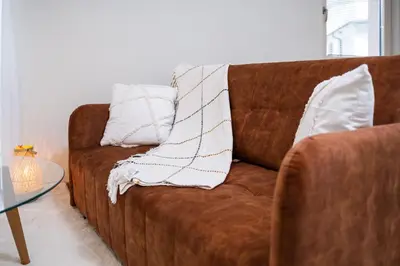 a brown couch with two white pillows on it at Stylish One-Bedroom Apartment in Plovdiv