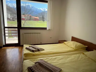 two beds in a room with a large window at Вила и тенис комплекс ,,Синьото