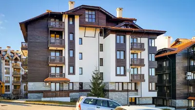 a large apartment building with a car parked in front at studio royal park bansko in Bansko