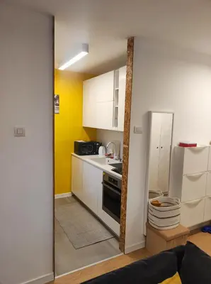 a small kitchen with white cabinets and a refrigerator at Апартамент Pavlin in Plovdiv
