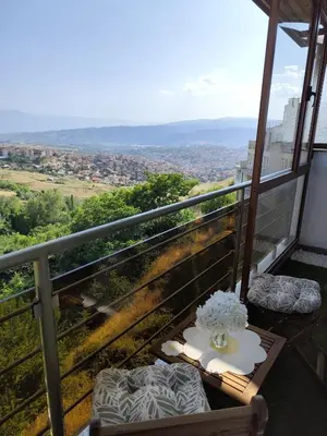 a table with a vase of flowers on a balcony at Sunny Hill Sandanski in Sandanski