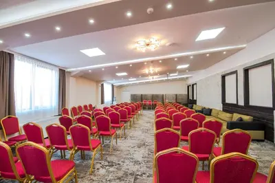 a conference room with red chairs and a stage at Hotel Zara in Bansko