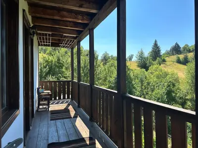 a porch of a cabin with a view of the woods at Guest House Opa in Smolyan