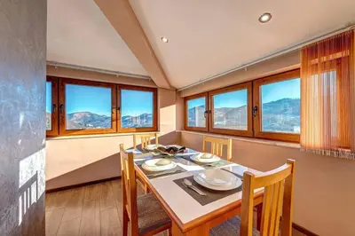 a dining room with a table and chairs and windows at Apartment Yana- The Amazing View in Smolyan