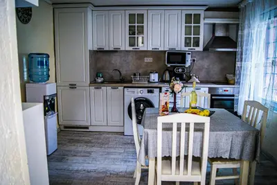 a kitchen with a table and chairs and a kitchen with white cabinets at NIKI Apart in Sofia