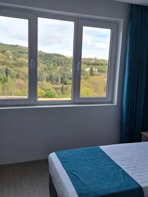 a bedroom with two windows and a bed with a view at Sandanski park view in Sandanski