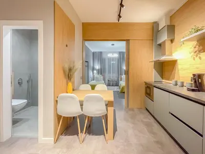 a kitchen with a wooden table and white chairs at Stylish City Center Apartment by NDK in Sofia