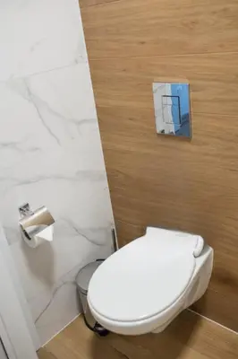a white toilet in a bathroom with marble walls at ТОП Апартаменти в Панорама Парк in Plovdiv