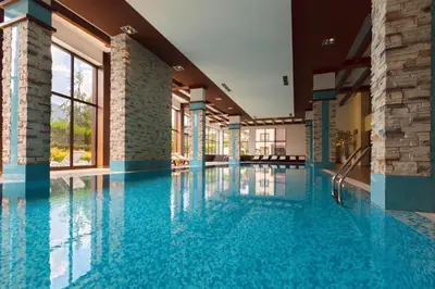 a large swimming pool with blue water in a building at TERRA COMPLEX D5 - Private apartment - Golf, Skiing & SPA in Razlog