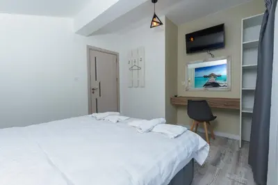 a bedroom with a white bed and a chair at ENEVI Guest Houses-Къщи за гости Еневи in Sandanski