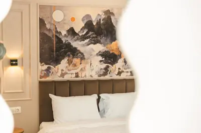 a bedroom with a painting above a bed with white pillows at ENEVI Guest Houses-Къщи за гости Еневи in Sandanski