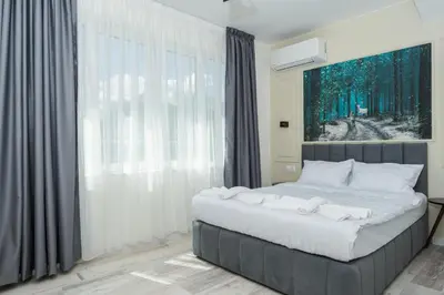 a bed in a bedroom with a large window at ENEVI Guest Houses-Къщи за гости Еневи in Sandanski