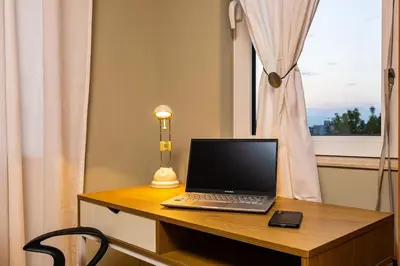 a laptop computer sitting on a desk next to a window at La Primavera Spacious Apartment in Plovdiv