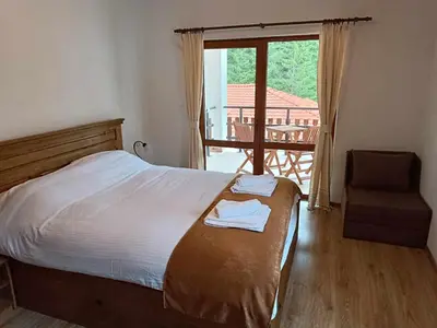 a bedroom with a bed and a chair and a window at Villa Victoria in Stoykite