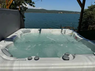 a hot tub with a view of the water at Villa Iskar Lake Residence by BookVillaBG in Shtarkelovo Gnezdo