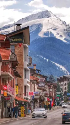 a street in a town with a snow covered mountain at lux apartament К602 in Bansko