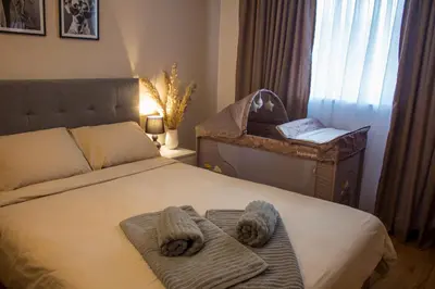 a bedroom with a bed and a crib with towels on it at EVIAS Apartment in Sandanski