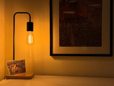 a lamp on a table with a picture on the wall at Cozy and quiet central apartment in Sofia