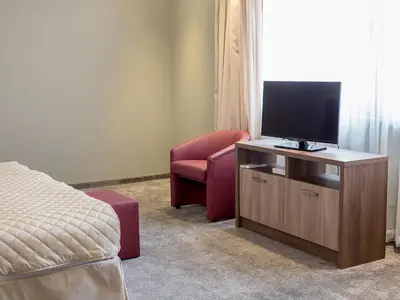 a bedroom with a bed and a tv and a chair at Hotel Calipso Hotel in Sofia