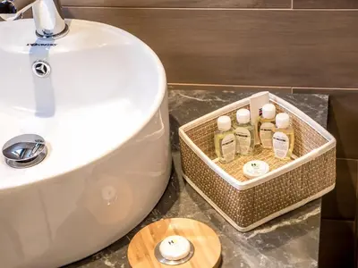 a bathroom with a toilet and a sink with bottles of soap at Hotel Calipso Hotel in Sofia