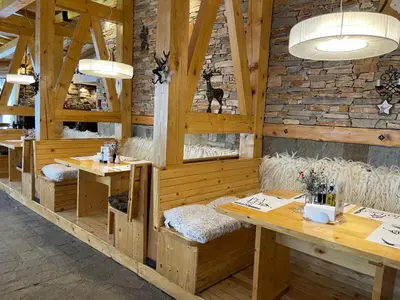 a restaurant with wooden tables and benches and a brick wall at The Castle Mountain Apartments in Pamporovo