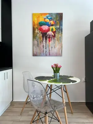 a table with chairs and a painting of people with umbrellas at Sao Paolo warm and cosy Studio in lively district in Sofia